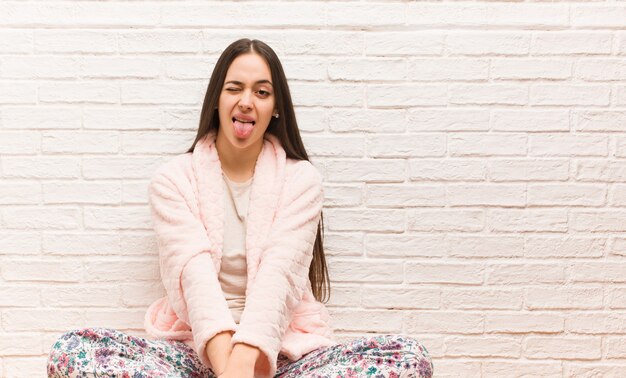 Photo young woman wearing pajama funnny and friendly showing tongue