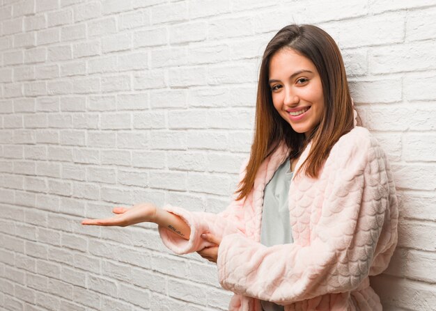 Young woman wearing pajama holding something with hands