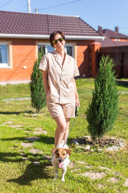 Young woman wearing pajama with her dog on backyard The concept of animals and friendship or pet owner and love