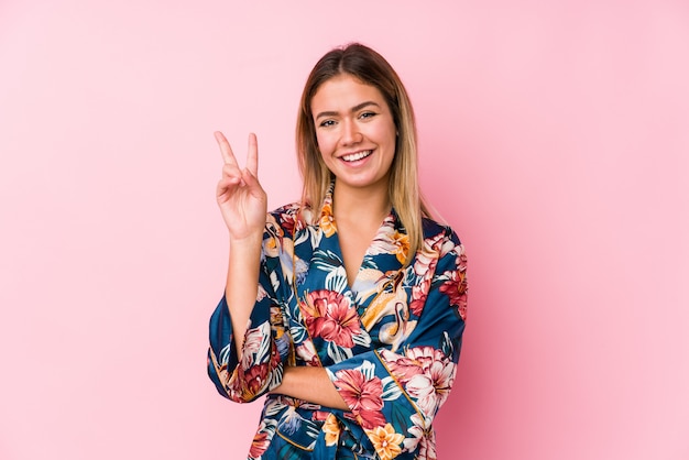 Young woman wearing pajamas showing number two with fingers.