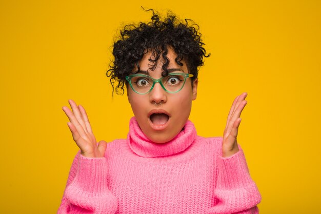 Молодая женщина в розовом свитере удивлена и шокирована