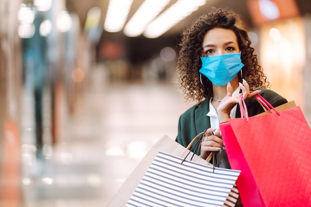 Young woman wearing protection face mask against coronavirus after shopping.