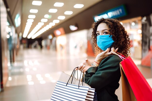 Young woman wearing protection face mask against coronavirus\
after shopping