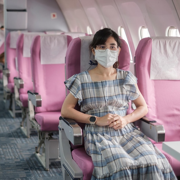 Young woman wearing protective face mask in airplane or public transportation, protection Coronavirus disease infection, Asian tourist ready to travel. Next Normal and reopening concept