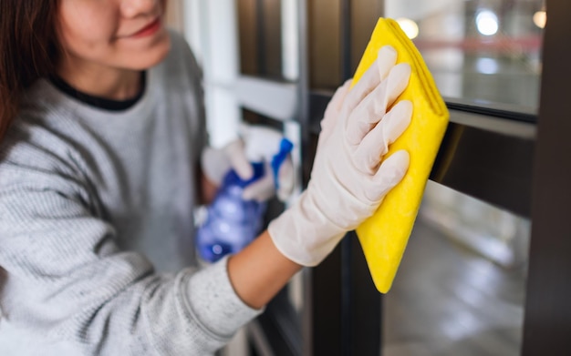 家事の概念のために窓を掃除する保護手袋を着用している若い女性