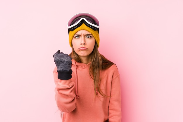 Young woman wearing a ski clothes isolated showing fist to front, aggressive facial expression