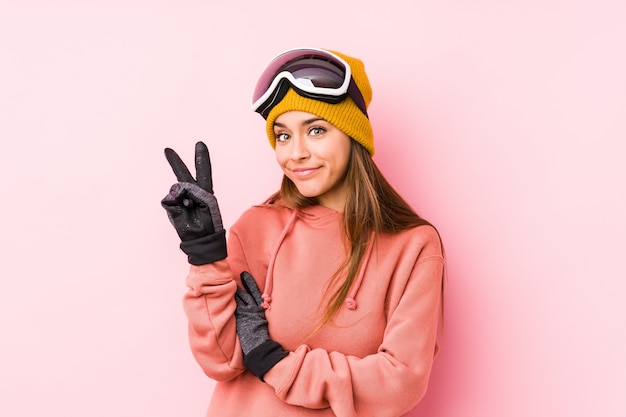 손가락으로 두 번째를 보여주는 스키 옷을 입고 젊은 여자