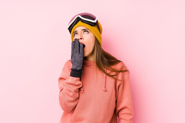 Young woman wearing a ski clothes yawning showing a tired gesture covering mouth with hand