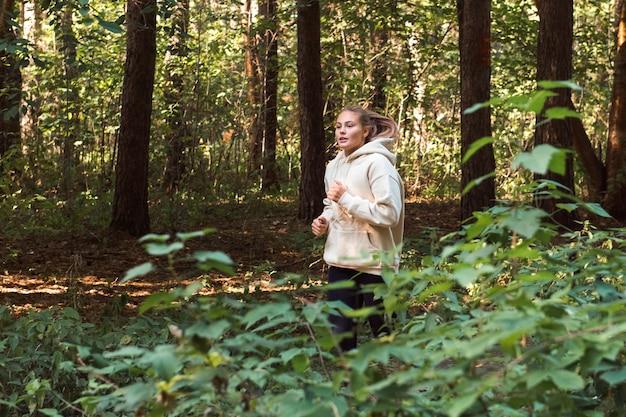 young woman wearing sport hoodie running in park healthy lifestyle and wellbeing concept