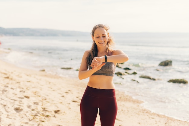 Young woman wearing sportswear is checking the data on her wrist smart watch.