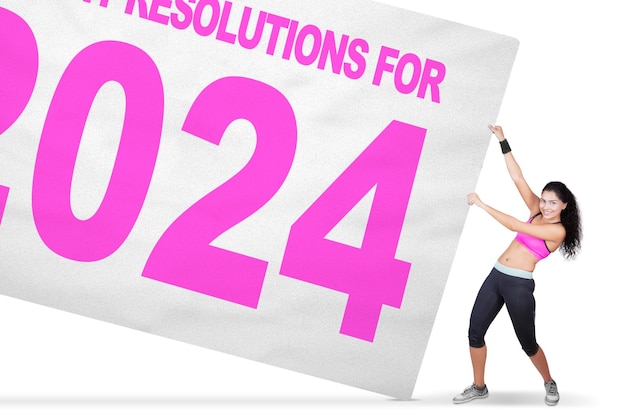 Young woman wearing sportswear while pulling a text of healthy resolutions for 2024 on the banner Isolated over white