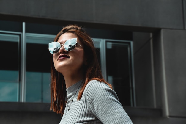 young woman wearing sunglasses against building