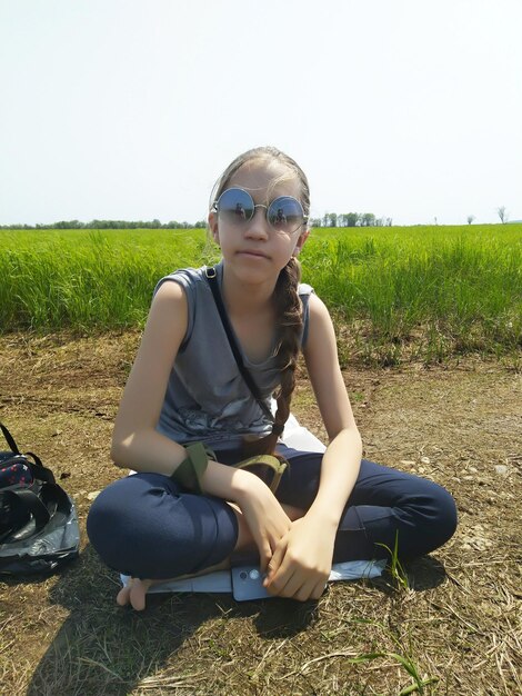 Photo young woman wearing sunglasses sitting on field