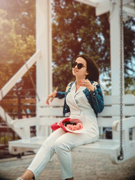 Photo young woman wearing sunglasses sitting on swing