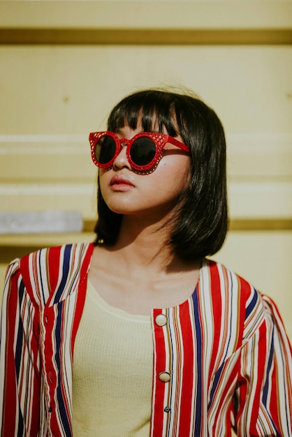 Young woman wearing sunglasses standing against building in city