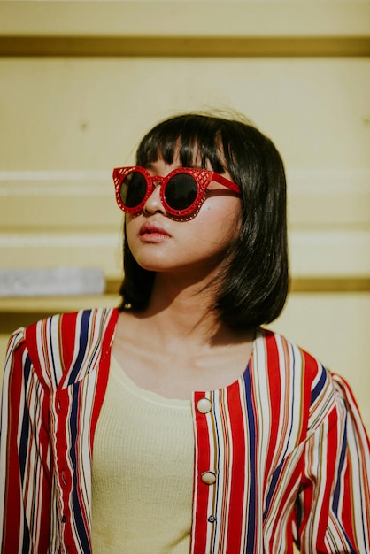 Photo young woman wearing sunglasses standing against building in city