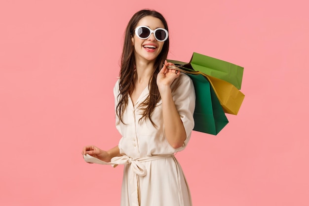 Young woman wearing sunglasses standing against gray background