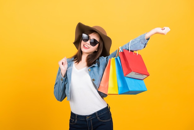 Young woman wearing sunglasses standing against yellow background