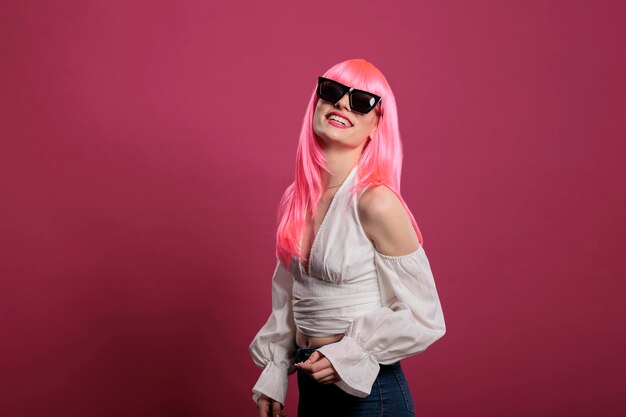 Young woman wearing sunglasses while standing against yellow background