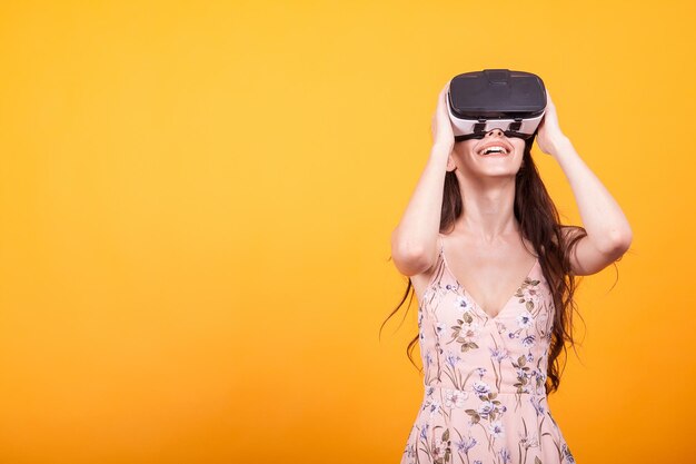 Young woman wearing sunglasses while standing against yellow background