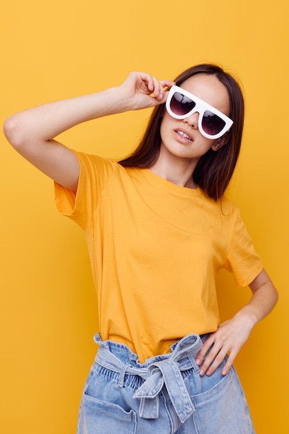 Young woman wearing sunglasses while standing against yellow background