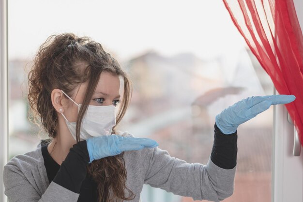 Photo young woman wearing surgical mask and gloves is doing funny movements with her hands