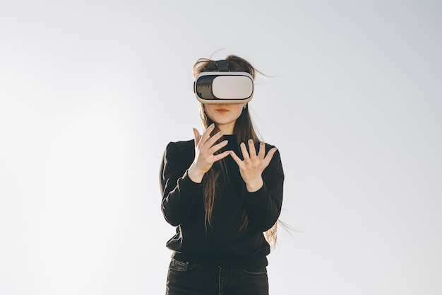 Young woman wearing vr glasses, headset, playing virtual games and watching videos outdoors