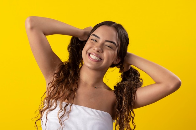 Young woman wearing white dress smiling on a yellow background