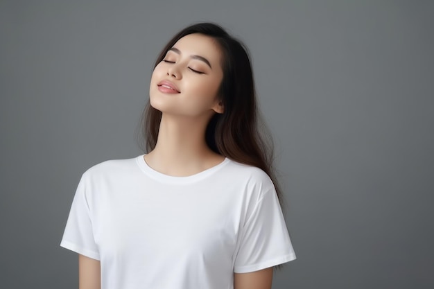 Photo young woman wearing a white tshirt feels happy and relaxed on a gray background