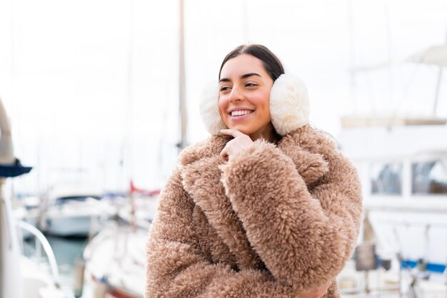 Young woman wearing winter muffs at outdoors looking to the side