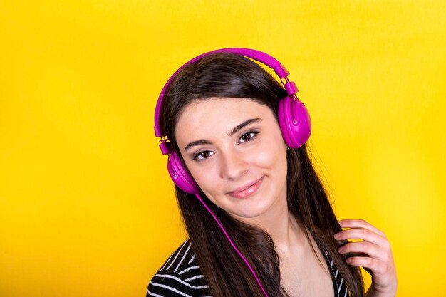 The young woman wears jeans and a striped t-shirt and uses headphones to listen to music