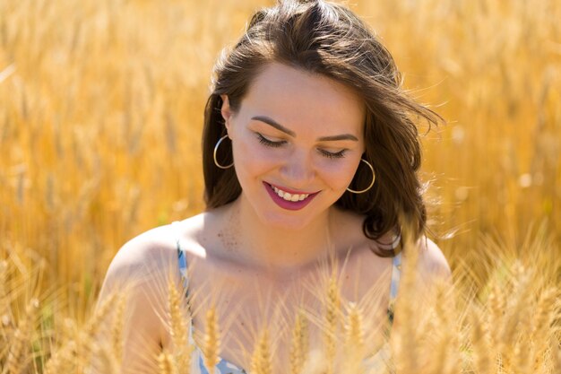 Young woman in wheat field at sunset