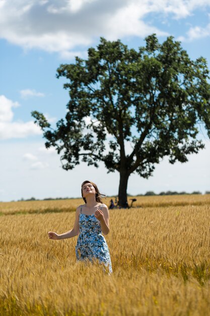 Young woman in wheat field at sunset