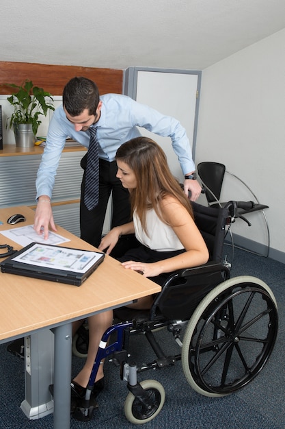 Young woman in wheelchair working with a male colleague