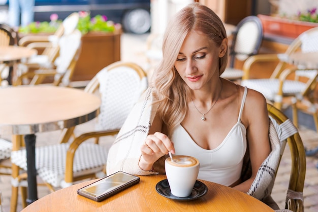 Young woman while relaxing in cafe at table on street happy caucasian woman