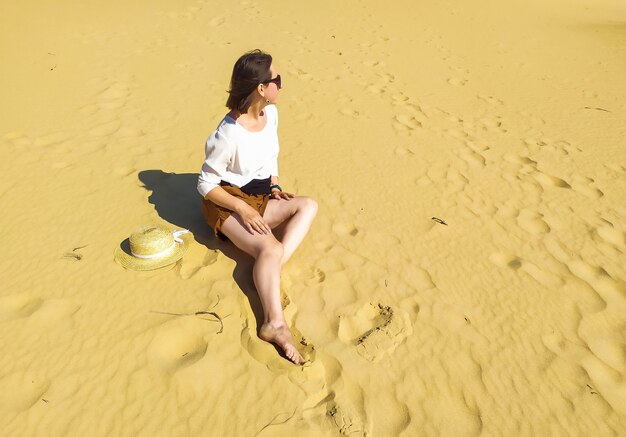 Young woman in white blouse and brown shorts walking in desert