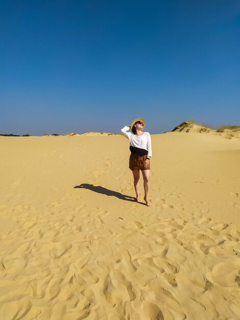 Young woman in white blouse and brown shorts walking in desert