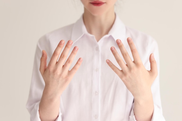 Giovane donna in camicetta bianca mostra le mani paziente femminile mostra la pelle al dermatologo in moderno