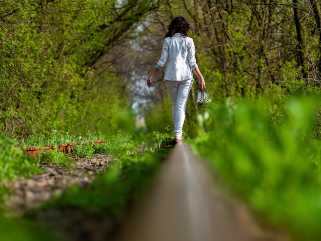 A young woman in white clothes is walking on rails