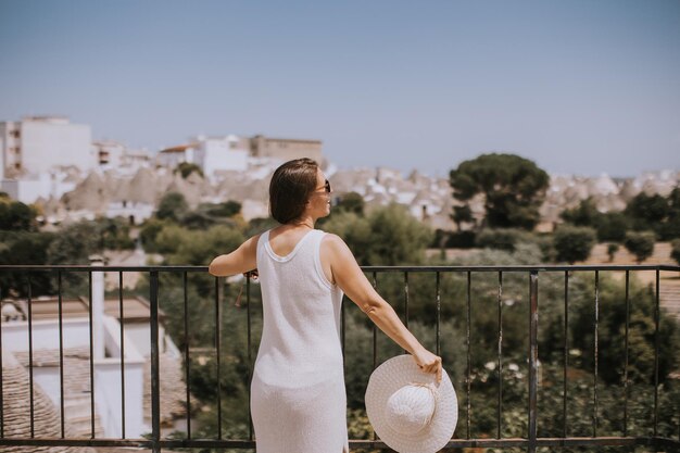 A young woman in a white dress and hat on a sunny day during tourist visit in Alberobello Italy