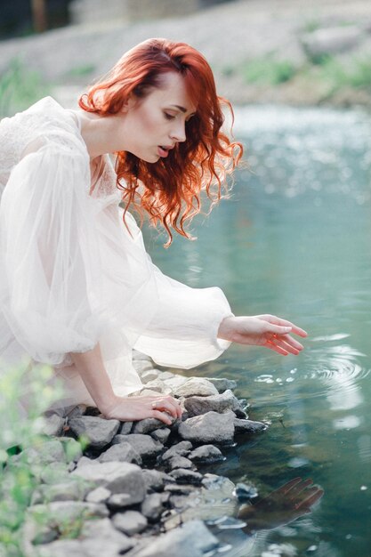 Foto giovane donna con un vestito bianco vicino al fiume