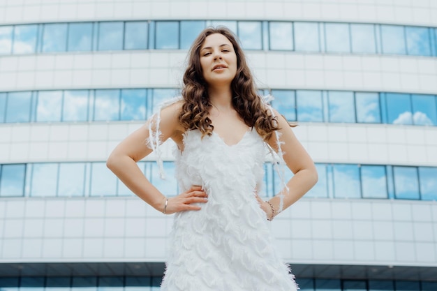 A young woman in a white dress poses outside The model is in a good mood walking in the city