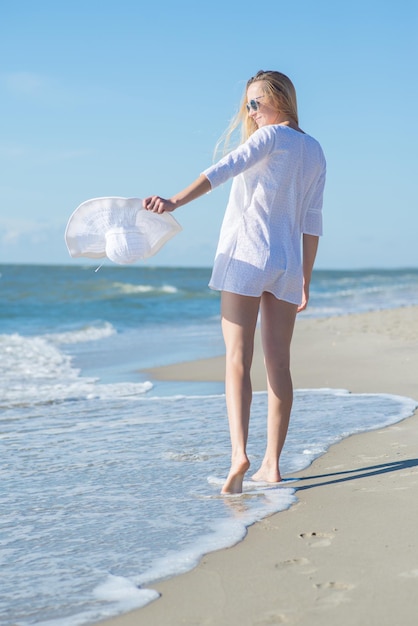 Photo young woman in white dress walking by the beach