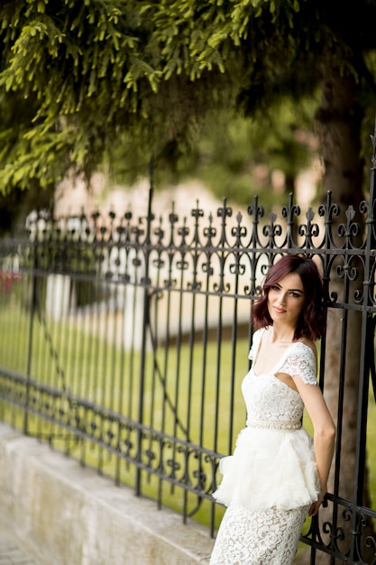 Young woman in white drress by the fence