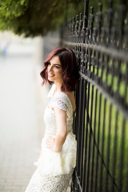 Young woman in white drress by the fence