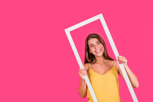 Young woman in white frame on pink background