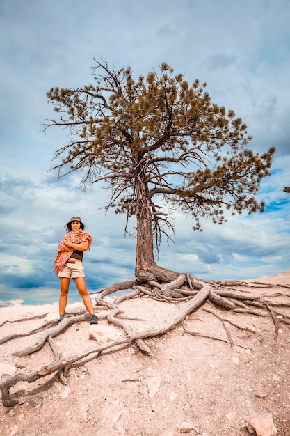 A young woman in a white half-dead tree on a Bryce viewpoint. Utah, United States