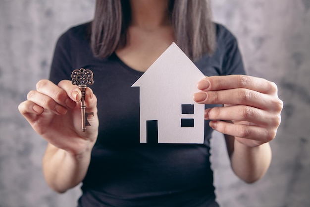 A young woman in white holds a house