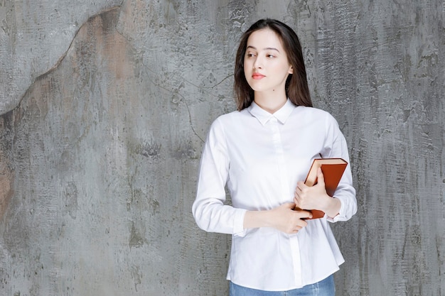 Young woman in white shirt holding book for her class. High quality photo