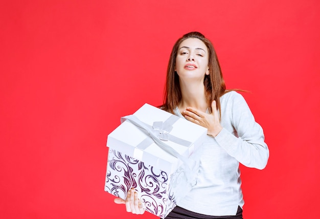 Young woman in white shirt holding a printed gift box